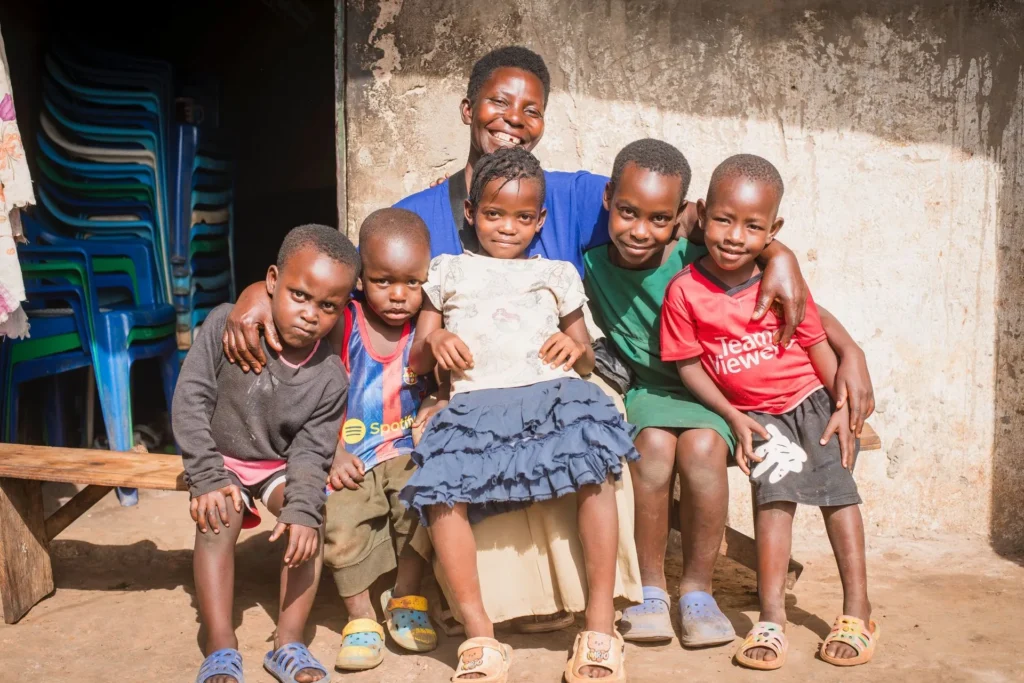 A mother sitting on a bench outside her home with five young children