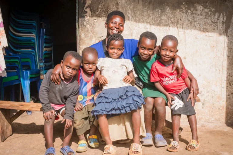 A mother sitting on a bench outside her home with five young children