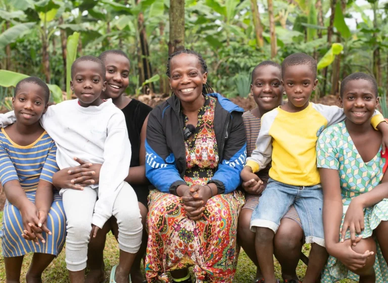 A mother seated with her children in a banana garden in Uganda, all smiling