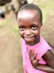 A young girl in a pink top looking up and smiling