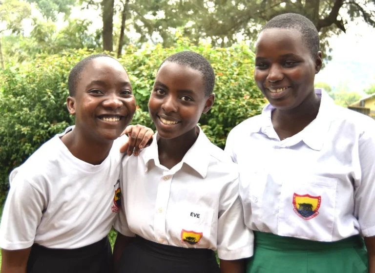 Three secondary school students in uniform smiling together outdoors