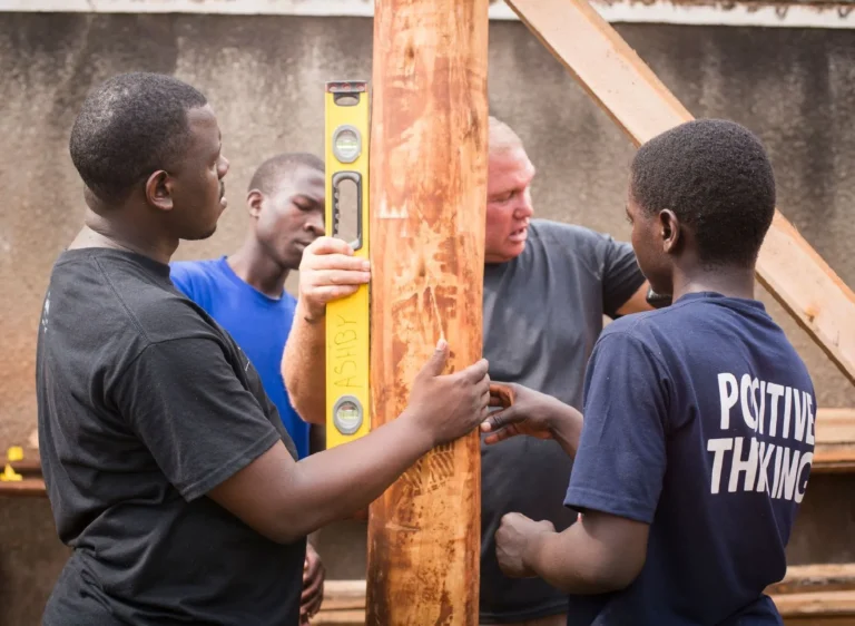 Young men checking a timber post with a spirit level during carpentry training