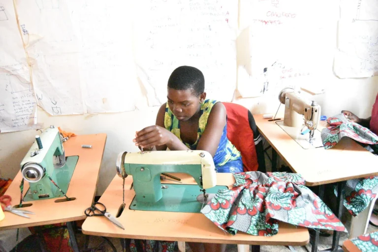 A young woman sewing at a machine in a vocational skills classroom